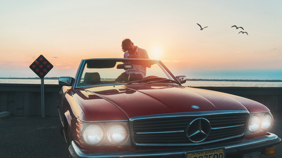 Man Car Sunset Ocean Bird Wind Мужчина сидит на заднем сиденье автомобиля без крыши на фоне заката солнца около океана летают чайки