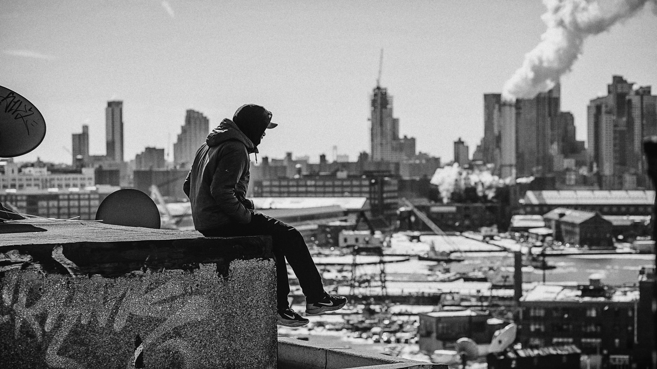 Urban Black White City Roof Man NYC BW Чернокожий мужчина сидит на крыше здания на фоне урбанистического города Америки