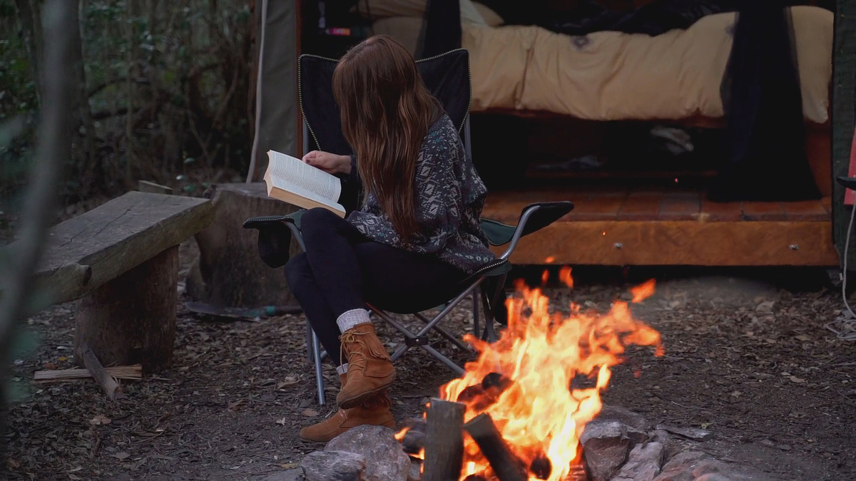 Woman Forest Camping Sitting Read Book Bonfire Девушка в теплом свитере сидит на походном стуле и читает книгу около костра