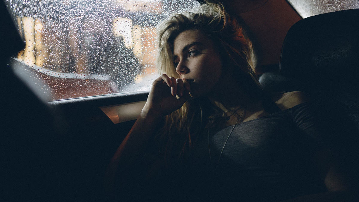 Woman Blonde Car Taxi Back Seat Rain Девушка брюнетка сидит в такси на заднем сиденье прислонившись головой в окну на улице идет дождь